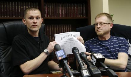 Michael and Eli Hall, right, hold their marriage license certificate, Tuesday, Dec. 3, 2013 as they talk to reporters in Seattle.