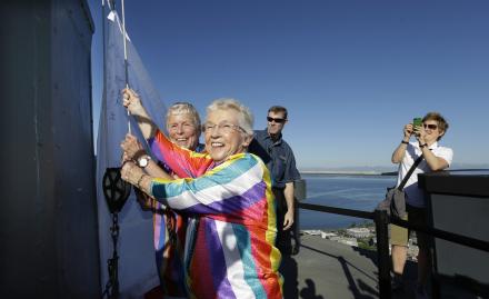 Jane Abbott Lighty, left, and her wife Pete-e Petersen turn toward photographers and supporters as they take a turn raising a giant marriage equality flag atop the Space Needle Sunday, June 30, 2013, in Seattle.