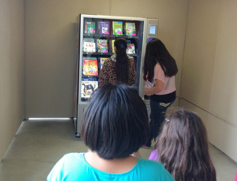 Children line up at multiple library vending machine sites.