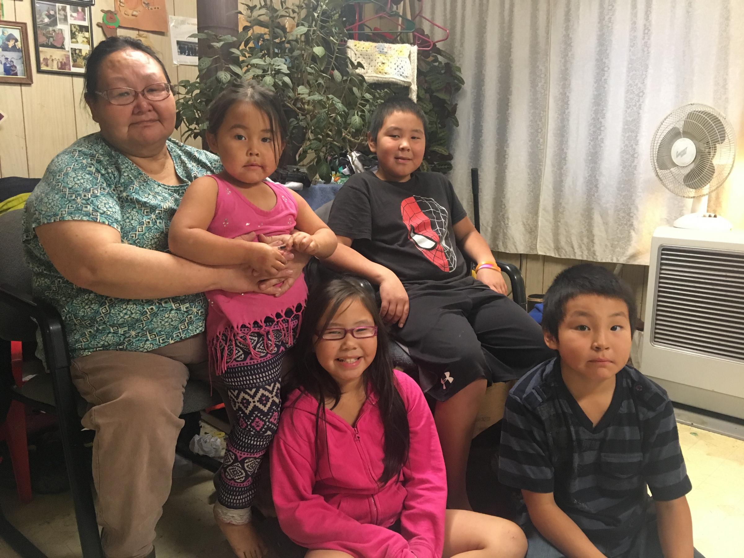 Yolanda Kelly poses with her granddaughter, son, and other children in her Emmonak living room. (Photo by Adrian Wagner/KYUK) 