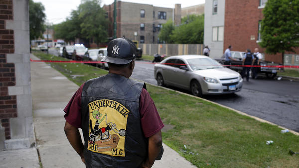 A bystander watches as Chicago police investigate a street where multiple people were shot on Sunday.