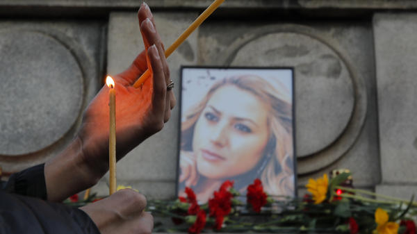 A woman holds a candle next to a portrait of slain journalist Viktoria Marinova during a vigil at the Monument of Liberty in Ruse, Bulgaria, on Monday.