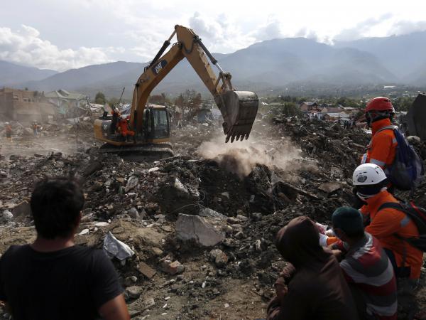 Rescue workers watch as a heavy machine dig through rubble searching for earthquake victims on Thursday in Palu, Central Sulawesi, Indonesia.