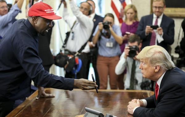 Rapper Kanye West shows a picture of a plane on a phone to President Trump during a meeting in the Oval Office on Thursday.