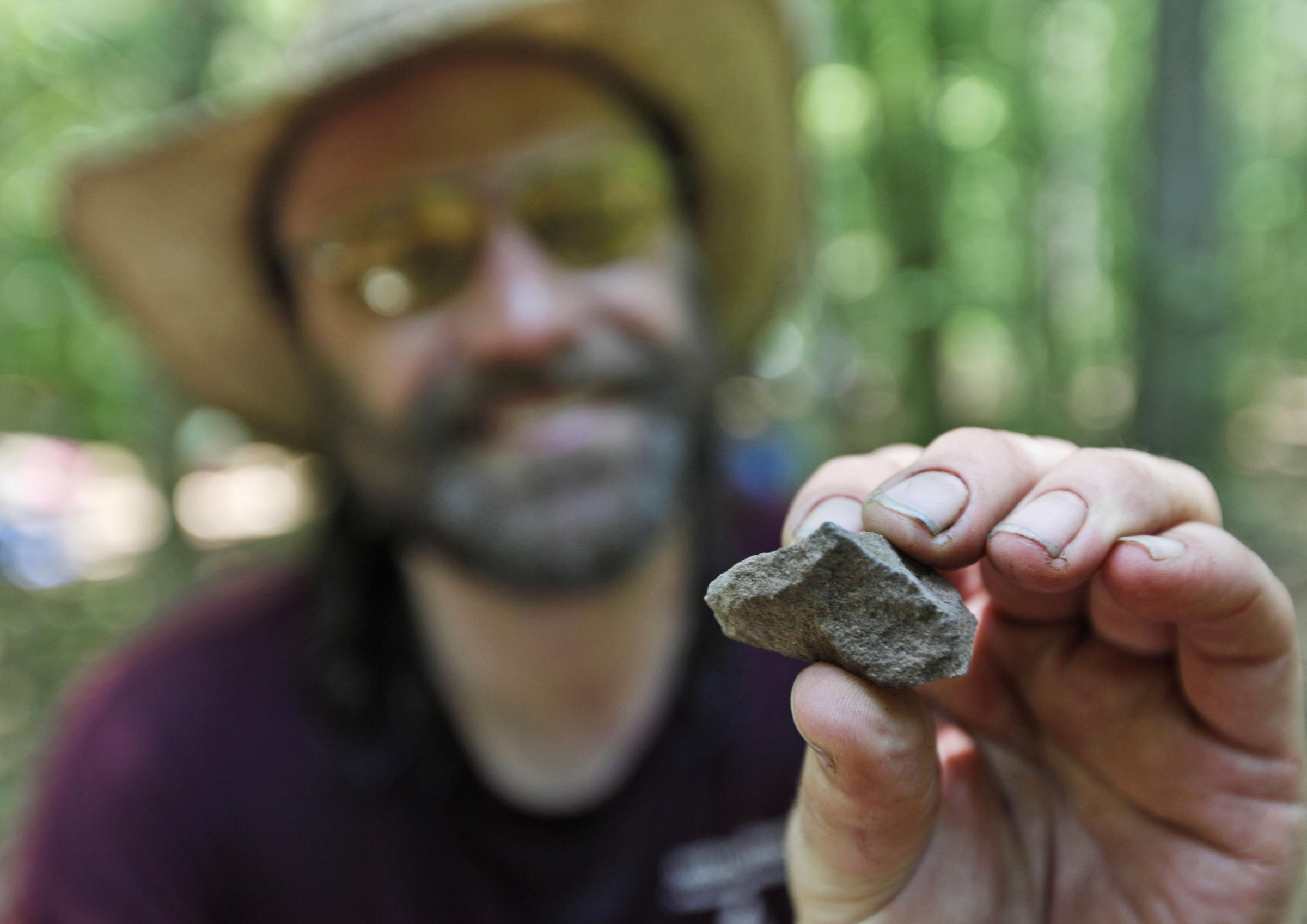 Daniel Sayers has been working for more than a decade in Great Dismal Swamp; here, in 2011, he displays a fire-cracked rock from a dig site. - 373520043
