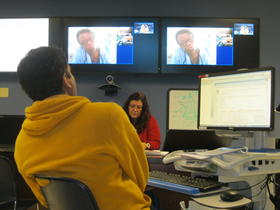 Dr. Shailesh Garg (foreground) in Miami advises Dr. Kathleen Charles (on video screens) in Haiti. 