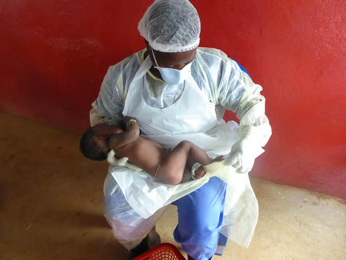 A health care worker gives some much needed maternal care to an infant whose mother died from Ebola.