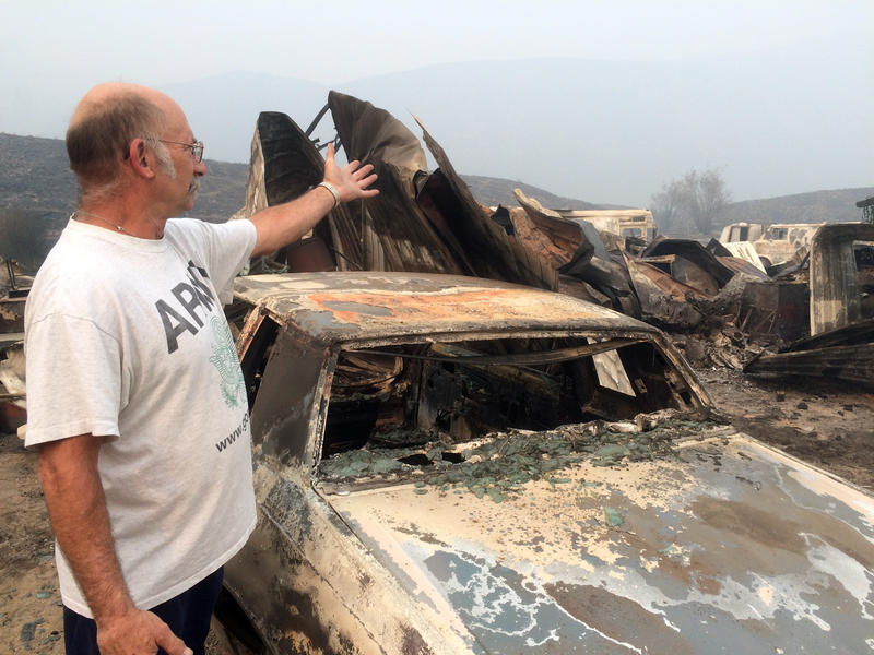Steve Surgeon surveys the ruins after he lost outbuildings and vehicles in a wildfire on the outskirts of Okanogan, Wash., Sunday, Aug. 23, 2015. His home was saved , though.
