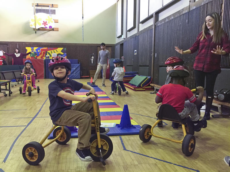 Kindergarteners take turns on the tricycles at the EEU gym class. 