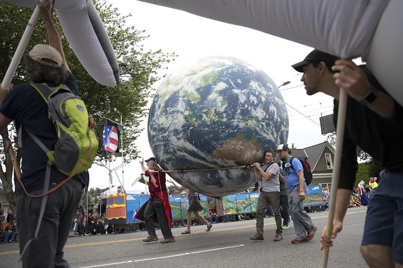 Parade-goers carry a blow-up planet Earth while marching in the Fremont Solstice Parade.