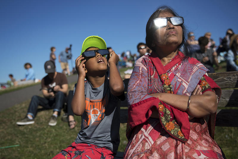 Ayush Jakhotia, 7, left, watches the solar eclipse with his grandmother, Radha Jakhotia, right, on Monday, August 21, 2017, from Gas Works Park, in Seattle. KUOW Photo/Megan Farmer