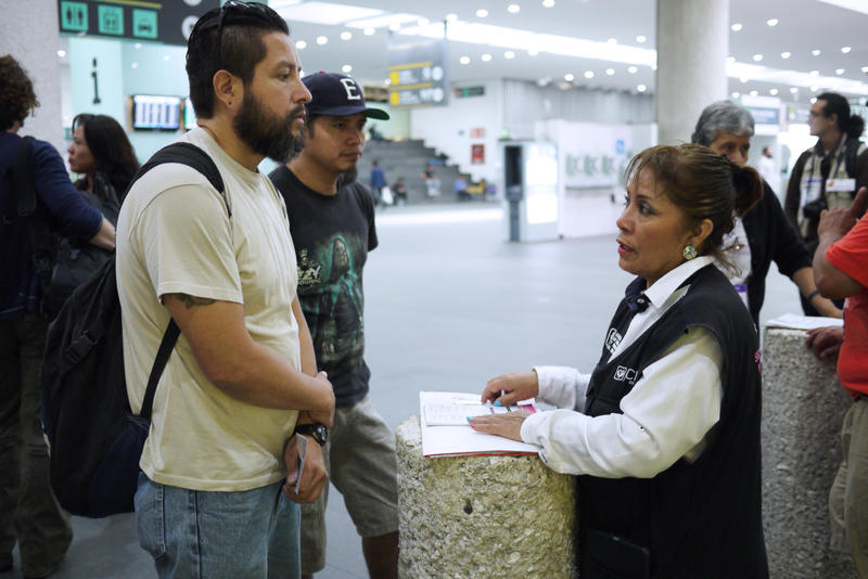 Gustavo Lavariega, a volunteer with Deportees United, talks with an official from Mexico's labor department as he waits for deportees to arrive on a flight from Texas.