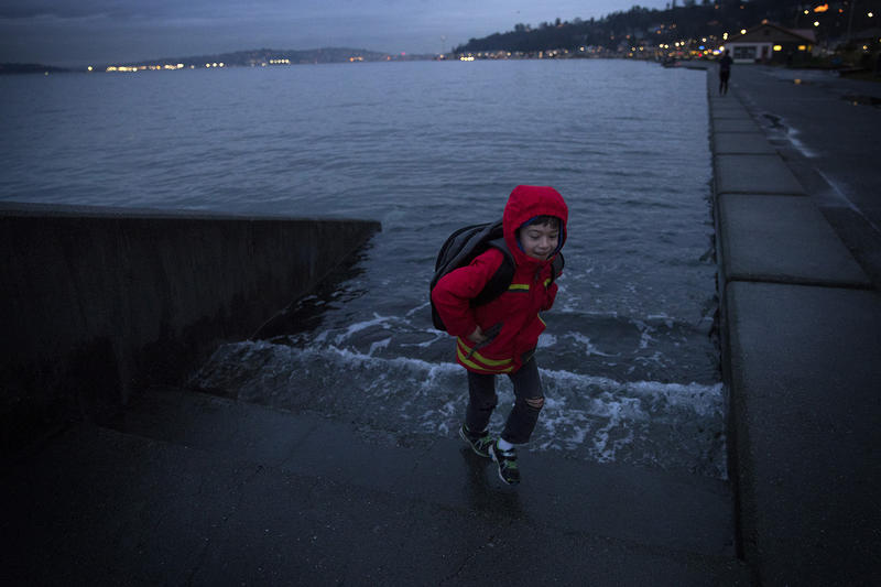 Ely Thomas, 7, runs from water spilling over a set of stairs that normally lead to the beach during a King Tide at Alki Beach Park on Friday, January 5, 2018, in West Seattle. 