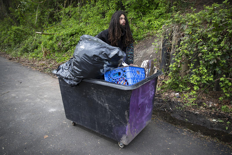 Ethan Kent, 26, uses a cart to transport his belongings as well as the belongings of friends away from a Ravenna encampment where he had been living for roughly a month and a half, on Wednesday, April 18, 2018, on the Burke-Gilman Trail in Seattle.