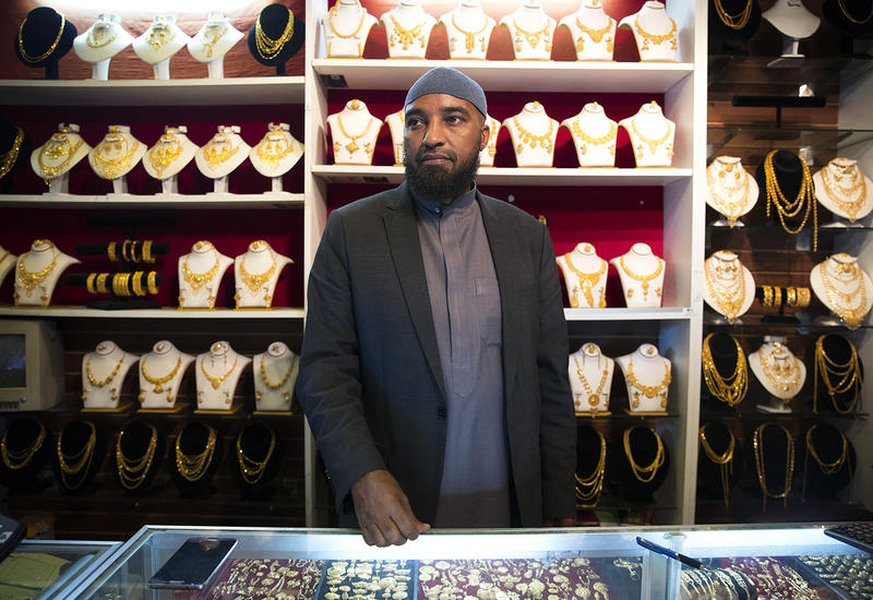 Ali Jama stands behind the counter of Havenice Day Jewelry on Thursday, April 19, 2018, in Tukwila. 