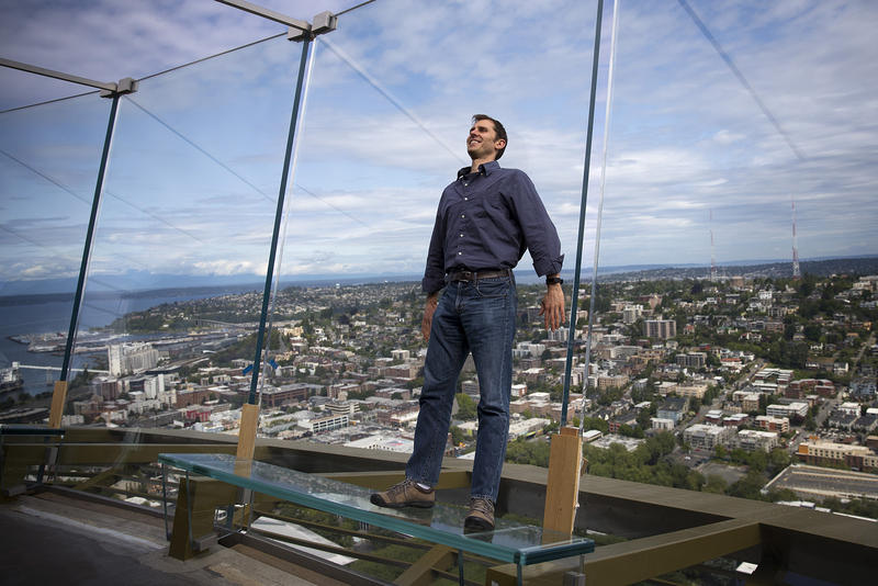 Derek Hanson stands on a glass bench on the observation deck of the Space Needle on Tuesday, June 5, 2018, in Seattle. Hanson asked KUOW what would happen to the Space Needle in the event of an earthquake. 