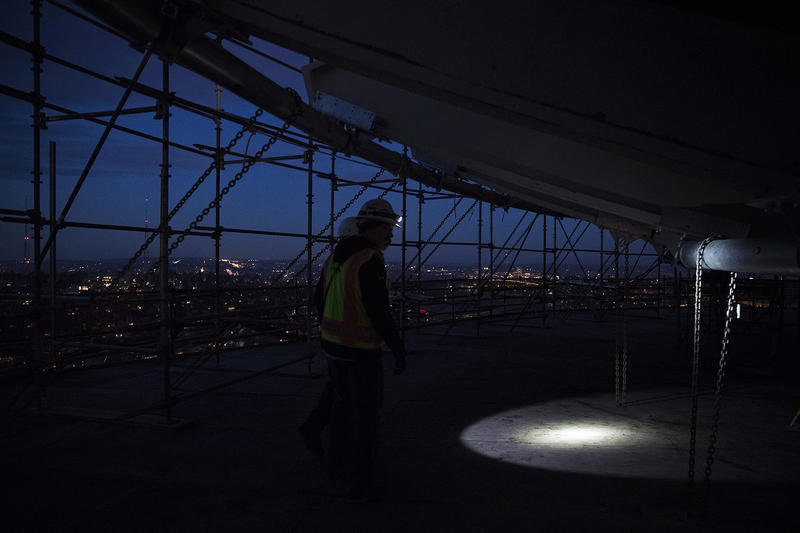 A construction worker uses a flashlight to exit the suspended scaffolding below the new rotating restaurant at the Space Needle on Monday, November 6, 2017, in Seattle.
