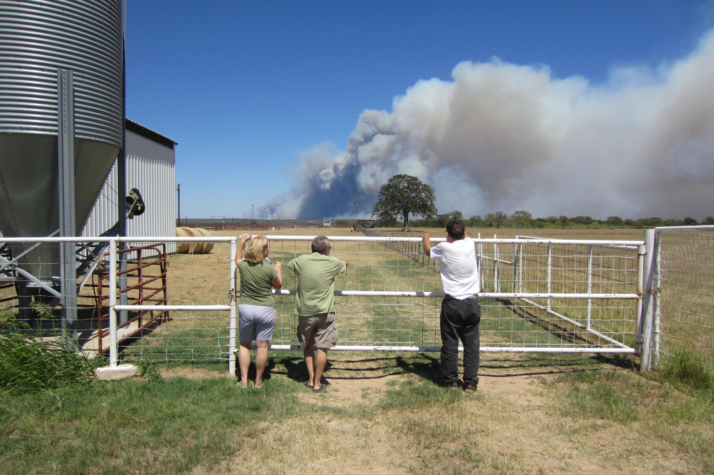 three people watch the fire from a livestock auction house