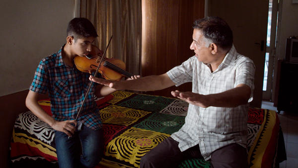 saleem khan, 65, teaches his grandson how to play the violin in