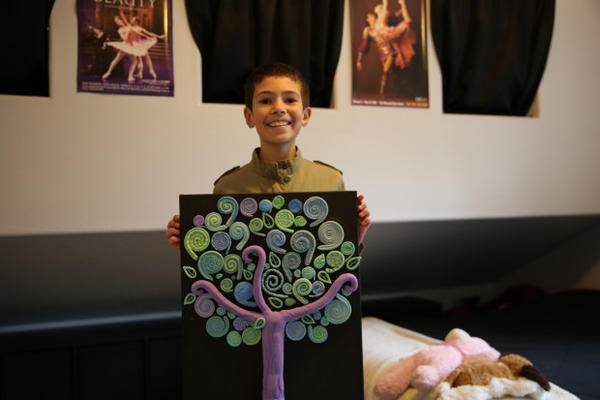 <p>Asjia Chapin, age 10, in her room, displaying one of her latest collages. She also writes poetry and does other art work.</p>
