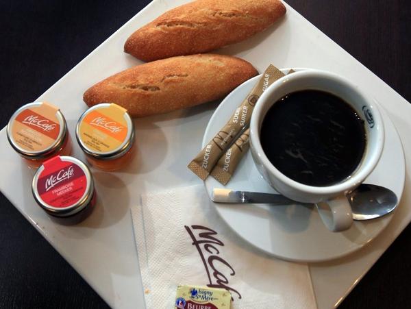 A McDonald's breakfast meal in Villeurbanne, France includes fresh baguettes and jam spreads with coffee for $4.55.