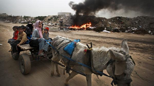 A Palestinian family rides on a donkey cart along a waste dump in Al-Nusirat, central Gaza Strip, in February. Living conditions continue to deteriorate for the 1.8 million Palestinians who reside in Gaza.