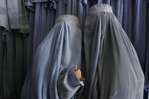 Two Afghan women clad in burqas whisper in a shop in Kabul, 2007. Despite advances in women's rights since the fall of the Taliban, most Afghan women, especially outside the capital, still opt for the all-enveloping cloak.