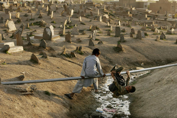 Boys play on a water pipe in a cemetery in Kabul, 2007.