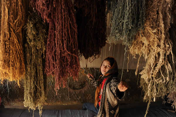 Ten-year-old Nahid grabs a thread while weaving carpet in her home in Kabul, 2010. Carpets, made mostly in the country's north, are one of Afghanistan's few major exports.