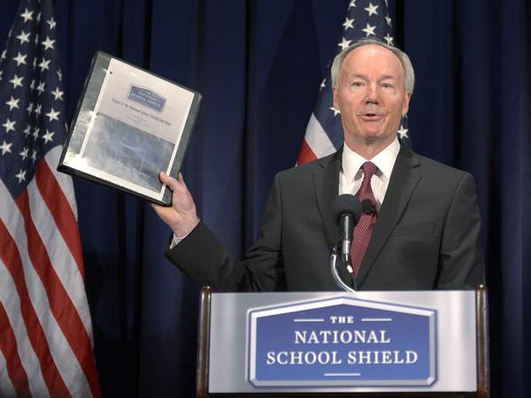 Former Republican Congressman Asa Hutchinson holds up his task force's report during a news  conference Tuesday in Washington, D.C.