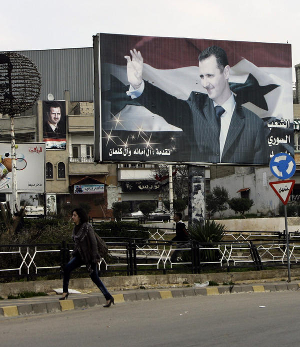 A Syrian woman walks past a poster for President Bashar Assad in an Alawite-dominated neighborhood in the western city of Homs, on Jan. 11, 2012. Support among the president's own minority sect is waning.
