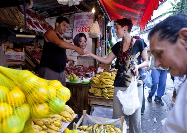 Tatiana Coelho buys fruit from a vendor in a favela in Rio de Janeiro, Brazil, on Sept. 20, 2012. Prices, especially for food, are skyrocketing in Brazil.