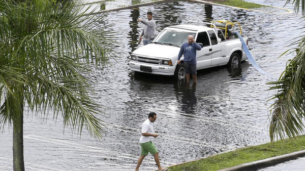 Workers pump water from the parking lot of the Dadeland Plaza shopping center on Thursday after heavy rains triggered by Tropical Storm Karen in Pinecrest, Fla., a suburb of Miami.