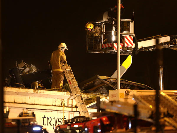 Firefighters work on the scene of a helicopter crash at The Clutha Bar in Glasgow, Scotland.