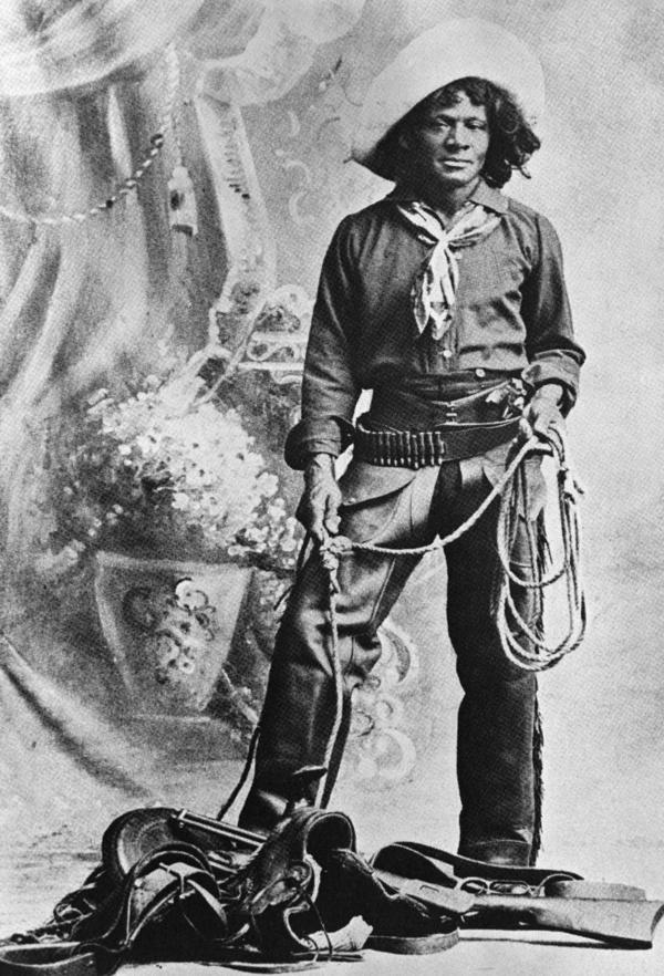 Nat Love, African American cowboy who claimed to have won the name of Deadwood Dick in South Dakota, 1876, by virtue of his roping talent. Full length photo with lariat and saddle. From his privately published autobiography (1907).