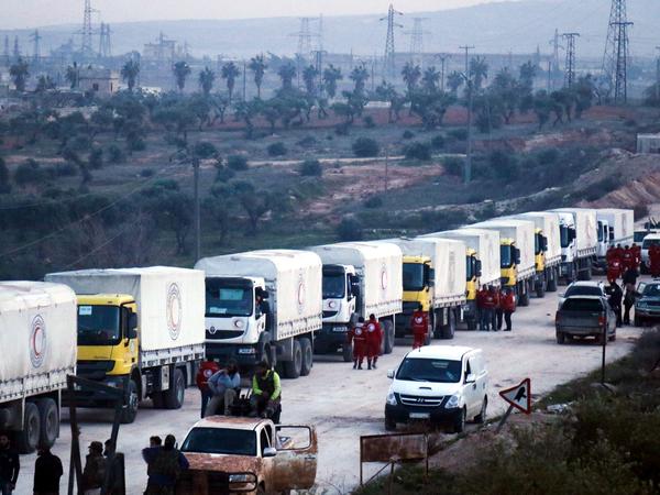 A convoy of vehicles carrying humanitarian aid sent by the United Nations moves toward the villages of Fua and Kafraya in Syria's Idlib province.