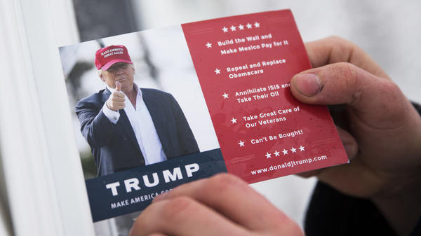 A volunteer for Republican presidential candidate Donald Trump leaves a card in a front door as he canvasses a neighborhood in New Hampshire.