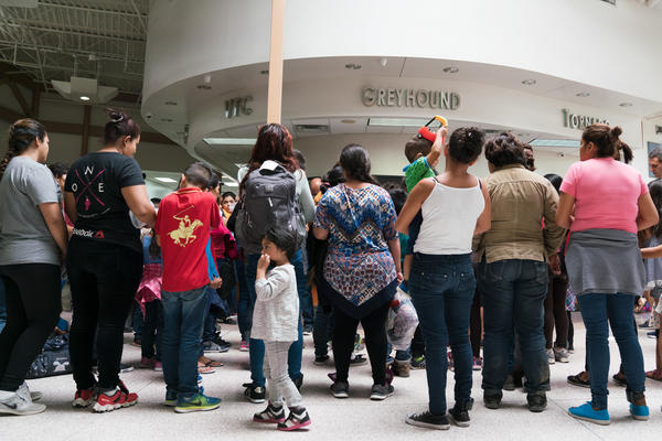 Migrants wait to receive bus tickets to destinations across the country. Adults wear ankle monitors so the government can ensure they check in with immigration officials once they reach their sponsors.