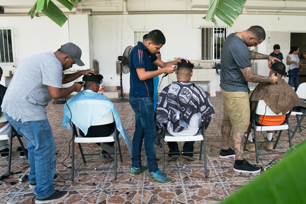 Volunteer barbers provide haircuts for migrants staying at the shelter.