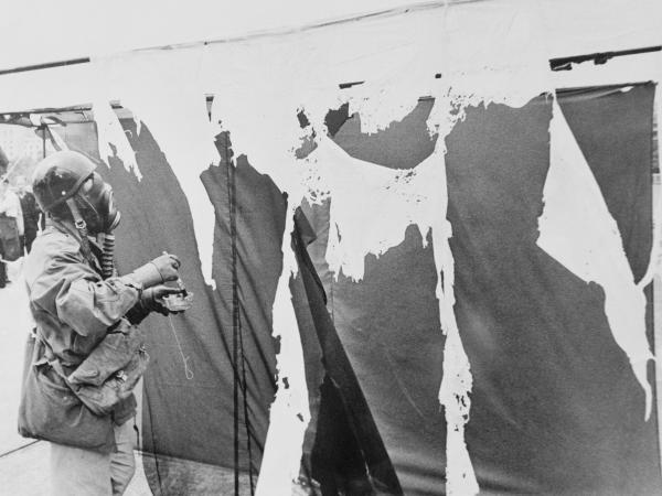 Metzger wears a gas mask while painting three nylon curtains with hydrochloric acid, causing them to disintegrate, in 1961.