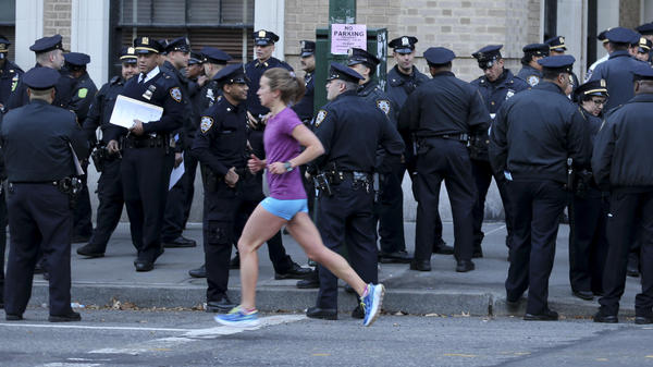 A runner moves past a group of police officers gathered near the finish line of the New York City Marathon on Nov. 6, 2016. Authorities are increasing the number of officers and other law enforcement personnel for this year's race, in the wake of Tuesday's terrorist attack in the city, in which a truck struck and killed eight bicyclists.