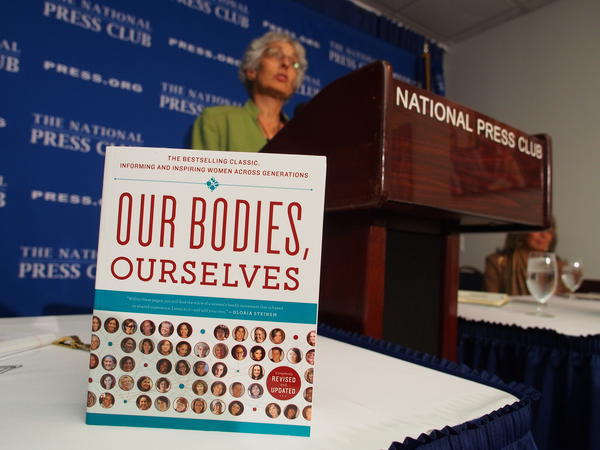 Judy Norsigian, executive director and founder of Our Bodies, Ourselves, speaks behind a copy of the women's health guide at the National Press Club in 2012.