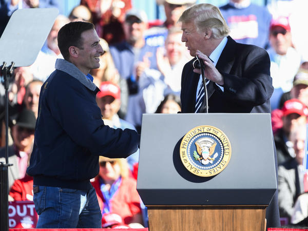 President Donald Trump shakes Nevada Republican candidate for governor candidate Adam Laxalt's hand at a campaign rally in Elko, Nev.