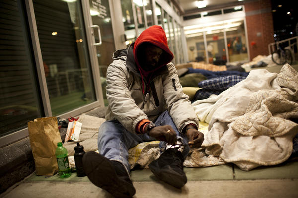 Albert Monroe and many others sleep on the porch and under the bright lights of the HCH clinic. Many say it's safer than sleeping under the highway or in city shelters, where theft and violence aren't uncommon.