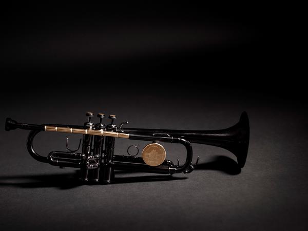 The Instrument of Hope is lacquered in black except for the shiny brass parts, which are clear lacquered. They include the lead pipe, which is made from bullets set end to end and drilled out so that air can flow through to make it a playable instrument. The tops of the three buttons are made of the sawn-off casing end caps or rims.