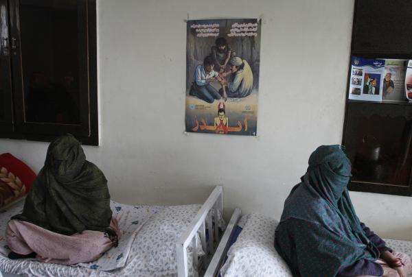 Two women sit, with their faces covered, at a drug treatment center in Kabul, Afghanistan.