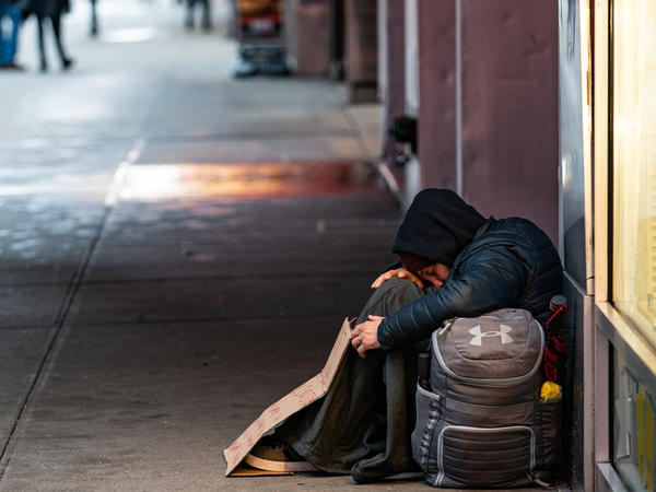 a homeless person sleeps on a sidewalk near time square on