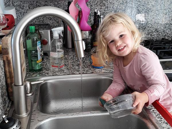 Rosy does dishes. Getting the 2-year-old involved in chores did lead to the kitchen being flooded and dishes being broken. But now she is still eager to help.
