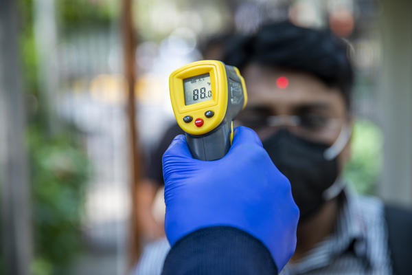 An office worker is screened with an infrared thermometer as he enters a building in New Delhi, India.