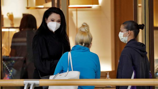 A salesperson left, wears a protective face mask as she talks to customers at the International Mall Wednesday, May 6, 2020, in Tampa, Fla.